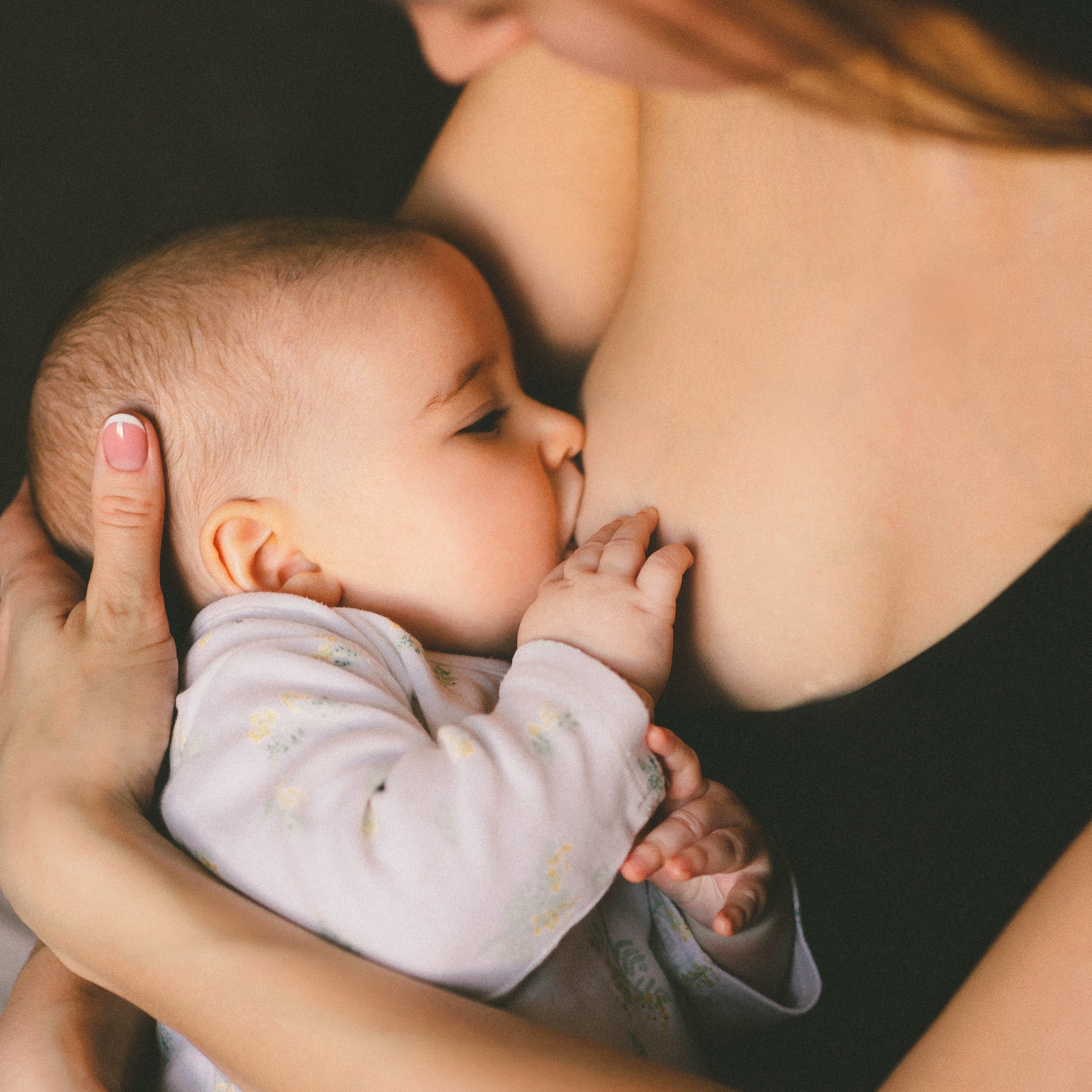 mother holding baby's head while breastfeeding